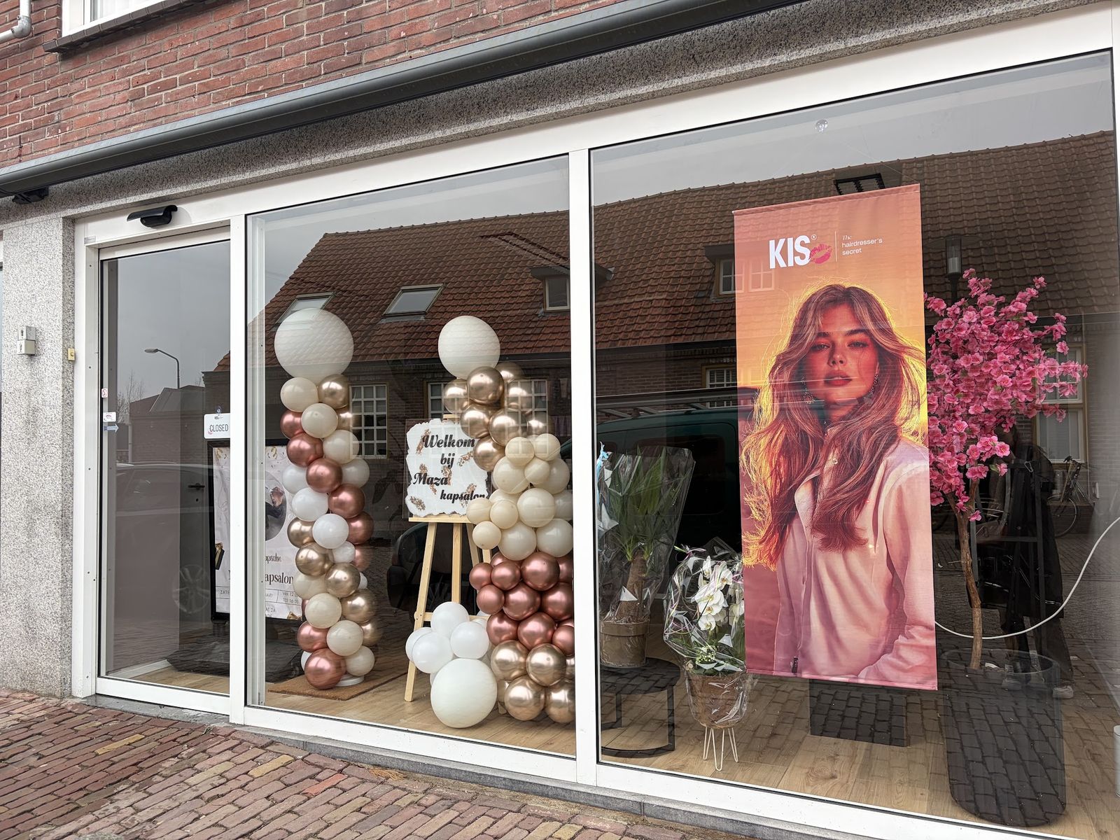 De gevel van Maza Kapsalon aan de Julianastraat op de openingsdag, met ballonnen en bloemen